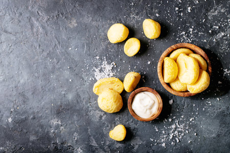 Fried potatoes served with tartar sauce and salt on dark texture backgroundの写真素材