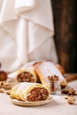 Apple strudel served with fresh apples, cinnamon sticks and walnuts over white texture backgroundの写真素材