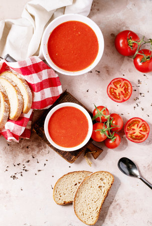 Homemade tomato soup served with fresh bio tomatoes and bread over white texture background. Top view, flat lay. Copy spaceの写真素材