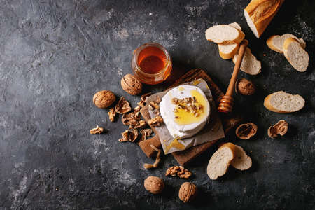 Goat cheese served with honey and walnuts over black texture background. Top view, flat lay. Copy spaceの写真素材