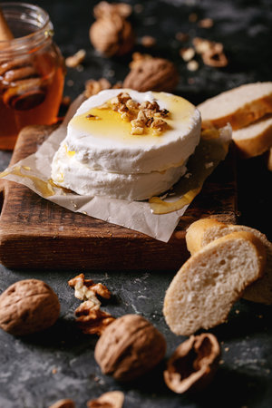 Goat cheese served with honey and walnuts over dark texture background. Copy spaceの写真素材