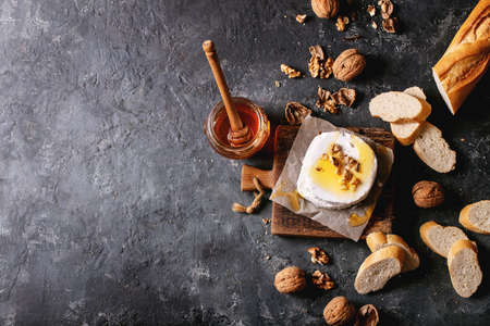 Goat cheese served with honey and walnuts over black texture background. Top view, flat lay. Copy spaceの写真素材