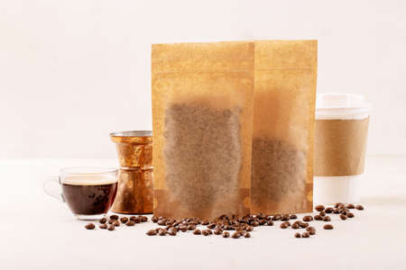 Take away paper cup, coffee beans, cup of glass esspresso, copper cezve and coffee packs with blank space for  over white texture background. Copy spaceの写真素材