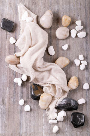 White, black decorative rocks and pebbles over grey wooden background. Top view, flat lay. Copy spaceの写真素材