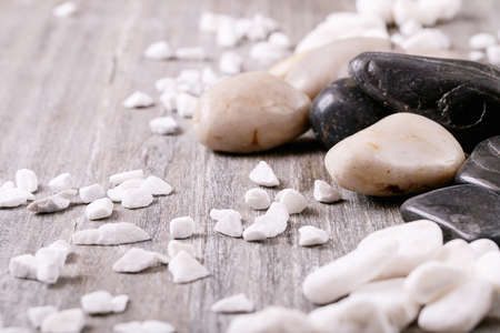 White, black decorative rocks and pebbles over grey wooden backgroundの写真素材