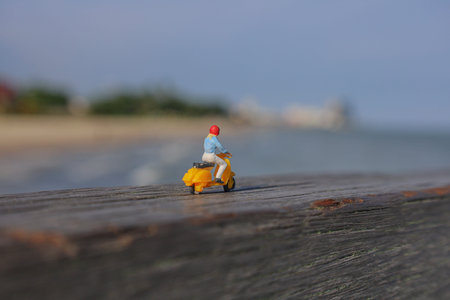 A miniature figure of a woman again was riding a motorcycle over a wooden fence against the beach