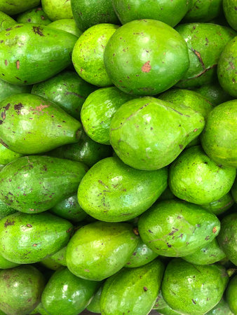 a stack of fresh avocado under indoor supermarket light