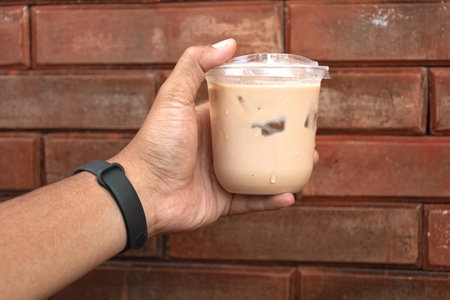 The hand that holds a glass of iced coffee latte