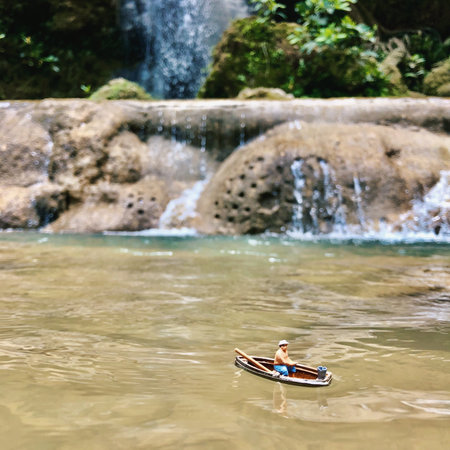 A miniature fisherman tries to fish a lake near the falls