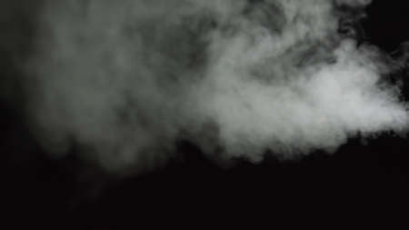 White water vapour on a black background. Close-up shot. White Fume Slowly Floating Rises Up. Abstract Haze Cloud. Animation Mist Effect. Smoke Stream Effect 4Kの写真素材