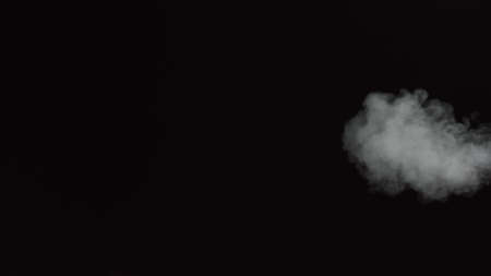 White water vapour on a black background. Close-up shot. White Fume Slowly Floating Rises Up. Abstract Haze Cloud. Animation Mist Effect. Smoke Stream Effect 4Kの写真素材