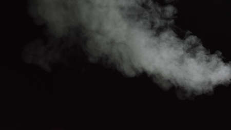 White water vapour on a black background. Close-up shot. White Fume Slowly Floating Rises Up. Abstract Haze Cloud. Animation Mist Effect. Smoke Stream Effect 4Kの写真素材