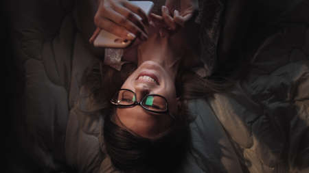 Sneaky Internet surfing. Pretty hacker girl surfing social network on smartphone sends messageの写真素材