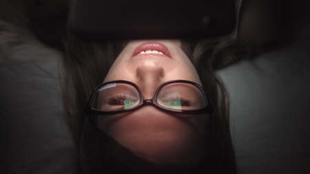 Women look at mobile phone on bed at nightの写真素材