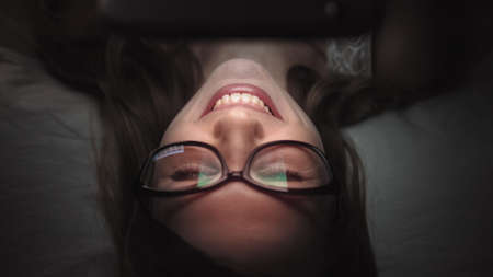 Women look at mobile phone on bed at nightの写真素材