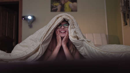 young girl watching a movie on a projector, rejoices showing emotionsの写真素材