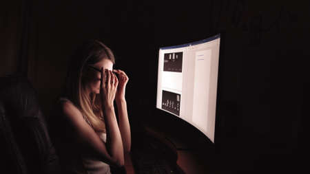 Young concentrated woman, sitting in her room or office .Studies late at night.Staying up late. Woman feeling headache and pain in the neck.の写真素材