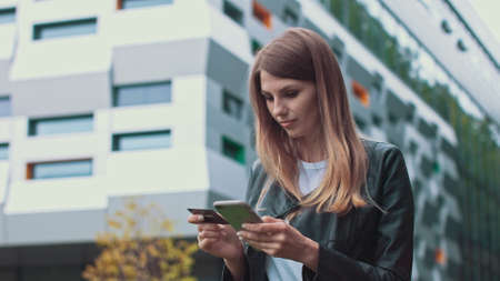 Smiling young female customer holding credit card and smartphone, on modern home background. Happy women shoppers using instant simple mobile payments while shopping online. Electronic banking serviceの写真素材