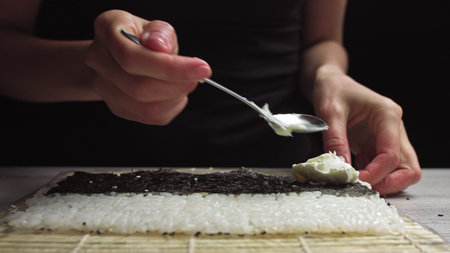 Close up of female hands of professional chef in gloves making delicious sushi rolls in restaurant kitchenの写真素材