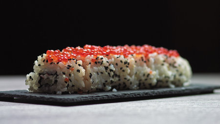 Sticks Take Sushi from Sushi box. Variety of types sushi with red caviar, fish, Philadelphia cheese and chopsticks close-up. Set of delicious Japanese sushi rolls.の写真素材