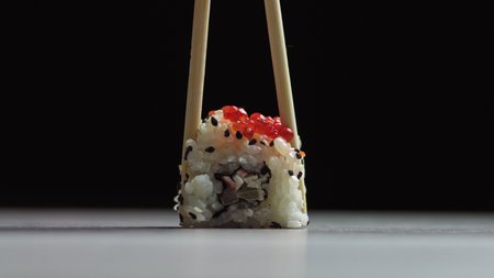 Chef cutting rolls of sushi with a knife on a stone board. - shot at a low angle. Beautiful female hands cut sushi.の写真素材