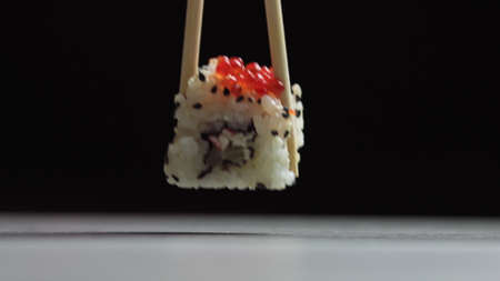Chef cutting rolls of sushi with a knife on a stone board. - shot at a low angle. Beautiful female hands cut sushi.の写真素材