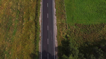 Aerial drone view of wide open empty road deep amongst wilderness forest with rolling hills and mountainsの写真素材