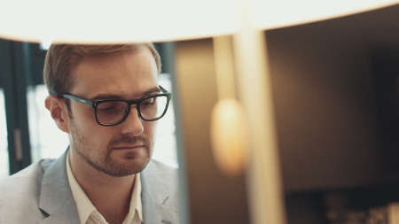 Male eyes in eyeglasses in front of laptop. Coder, programmer or developer using laptop. Close up of glassesの写真素材