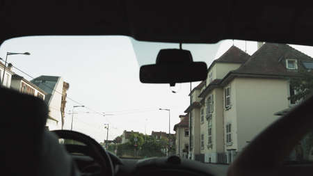A man rides in a car at sunset on the streets of a modern city. The navigator is included. Shooting from the back seat. Passes under the bridge and the train goes from aboveの写真素材