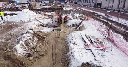 Engineers work with metal constructions while building a house. Aerial Flight Over a New Constructions Development Site. Top Down View at Contractors in Safety Hats.の写真素材