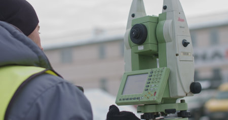 Worker Professional Surveying Engineer in the open space. A professional surveyor takes action with a theodolite using a digital optical device to measure the coordinateの写真素材