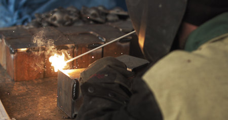 Close-up blacksmith welder in protective mask works with metal using a welding machine, bright...