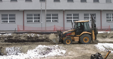 The bulldozer works on a construction site with sand, side view. New Big Tractor, a bulldozer on wheels on a sandy road on a construction site levels the site for the construction of real estateの写真素材