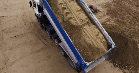 Dump truck unloading soil or sand at construction siteの写真素材