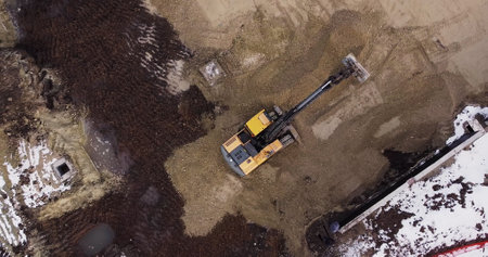 An Industrial Excavator On An Open Road Section Loads Rock And Earth On A Very Large Dump Truck, Loaded With Ore .The Excavator Bucket Drips And Loads The Ore.Panorama Of Construction Works.の写真素材