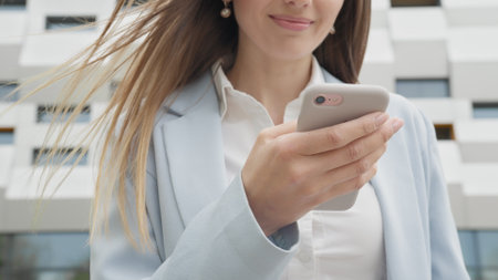 Appealing young elegant woman using social media application on smartphone text messages receive news smiling outdoor. People portraits. Technology. Closeup joyful girl reading good news on phone.の写真素材