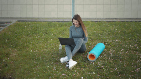 Happy woman, sitting laptop outdoor. Smiling fit girl typing on laptop computer at city background....