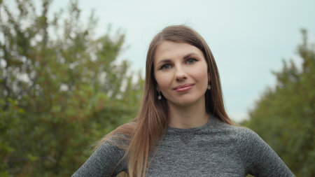 Young woman portrait. Portrait of happy beautiful positive fit girl, young slim fitness sports woman in sportswear, top outdoors going to training in park and smiling, looking at camera. Sport outdoorの写真素材