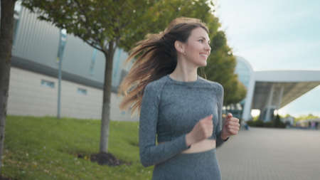 Young woman runner training in summer park city. Portrait of young and fit woman running and jogging alone on the empty street in city center wearing protective. Slow-motion shotの写真素材