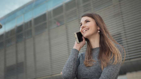 Fitness, sport and technology concept - happy smiling woman running outdoors. Close-up Of A Young Beautiful Sports Fitness Girl Holding A Smartphone In The Hands. Phone conversation during trainingの写真素材
