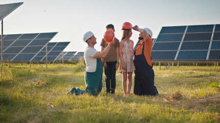 Two employees of the solar power plant brought their children to work and put a protective helmet on the childrens heads. Children at work with the parents of power plant engineers. Father and childの写真素材