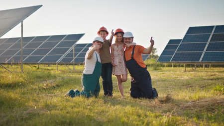 Two employees of the solar power plant brought their children to work and put a protective helmet on the childrens heads. Children at work with the parents of power plant engineers. Father and childの写真素材