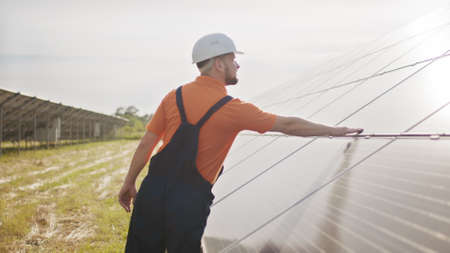 Assistance technical worker in uniform is checking an operation and efficiency performance of photovoltaic solar panels. Concept of electricity, ecology. Farm of solar panels. Green energyの写真素材