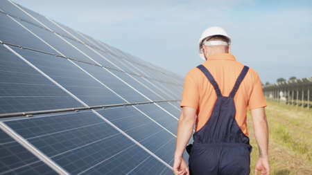 Sustainable green energy jobs, solar panel technician working with solar panels. Assistance technical worker in uniform is checking an operation and efficiency performance of photovoltaic solar panelsの写真素材