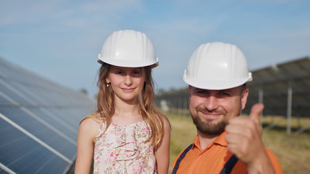 Father with little girl at solar power plant. The father talks about solar energy. The concept of...