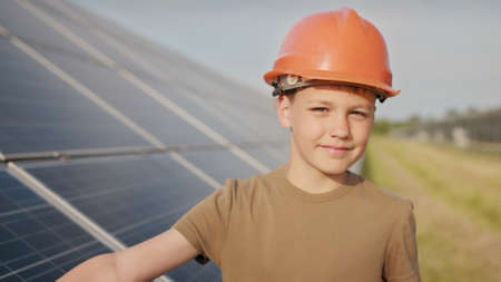 Little boy in a protective helmet at a solar power plant. The concept of children and green energetics. Children for clean energy. Shooting at a solar power plant. Ecological farm. Solar power stationの写真素材