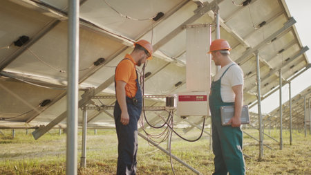 Workers installing PV Photovoltaic, solar panels, which converts solar energy into electric energy. Connecting and configuring solar panels to the network. Concept of green energy.の写真素材