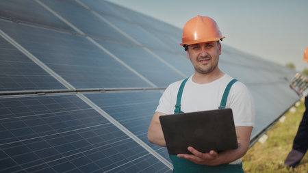 Engineer standing with Solar cell panels looking monitor of the Electric power value made from the...