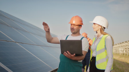 Technician and investor walking in Solar cell Farm through field of solar panels checking the panels...