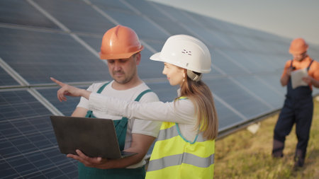 Technician and investor walking in Solar cell Farm through field of solar panels checking the panels at solar energy installation. Employees of power plant and talking about scheme of solar panels.の写真素材